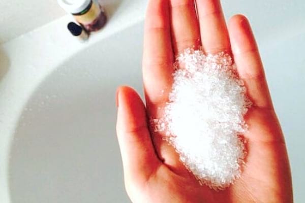 Une main avec du sel d'epsom à mettre dans le bain contre le torticolis