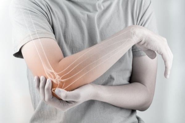 Une personne se tient le coude droit douloureux