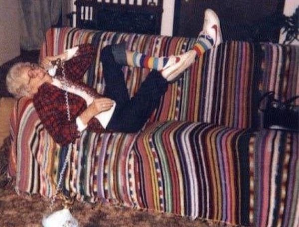 Une grand-mère avec des baskets Nike au pied au téléphone allongé sur un canapé 