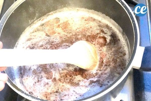 Un mélange d'eau et de graines de lin dans une casserole et une cuillère en bois