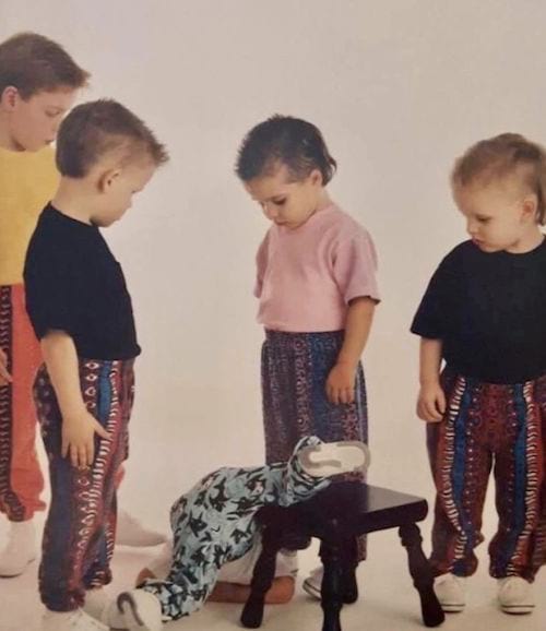 Petit garçon tombant d'un tabouret avec plusieurs autres petits garçon autour le regardant
