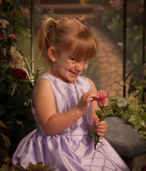 Une petite fille tenant une fleur avec un regard étrange 