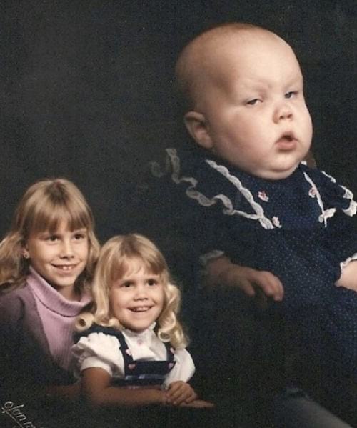 Deux petites filles souriante avec un bébé qui a l'air endormi 