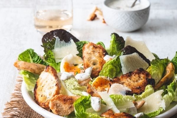 Ein Caesar-Salat auf einem Teller mit Eigelb hinzugefügt