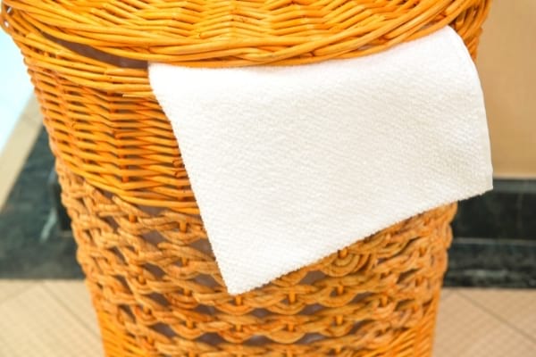 Une serviette blanche dans un panier de linge sale marron 