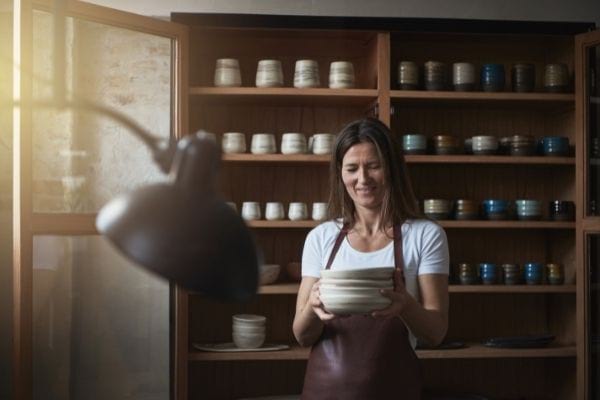 a woman is holding a stack of plates in a pottery store