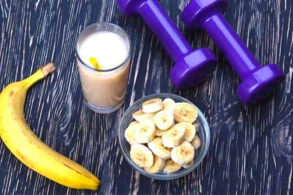 De la banane énergisante, du lait et des altères posés sur une table