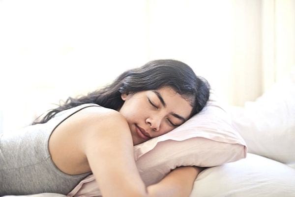 une jeune fille brune dort sur un coussin