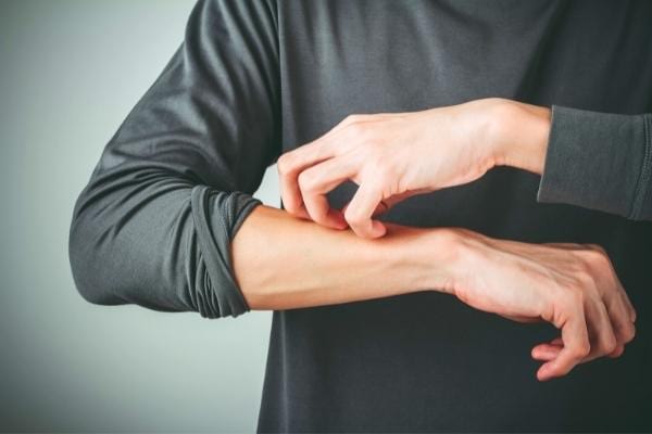 Un homme qui gratte son bras et qui se soulage grace à la peau de banane