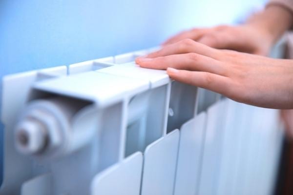 Des mains qui touchent un chauffage qui a été éteint pendant la journée