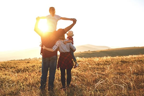 une famille de 4 personne devant un coucher de soleil à la campagne