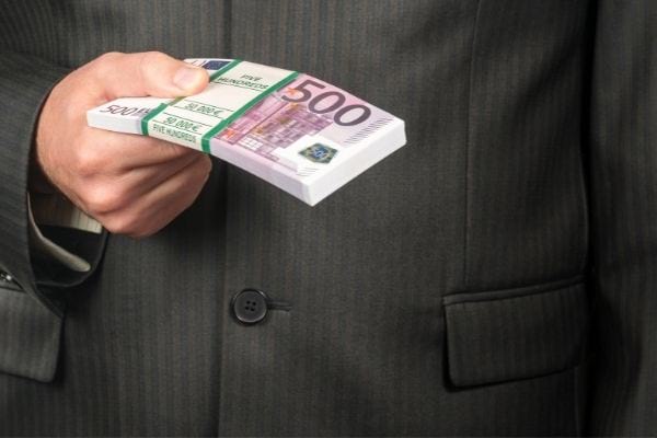 une liasse de billets de 50 tenus par un homme avec un veste noire