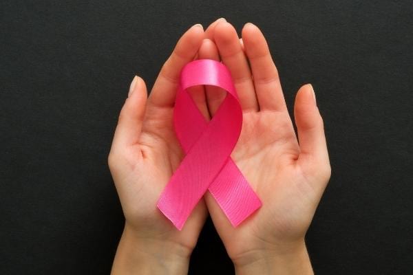 un ruban contre le cancer entre les mains