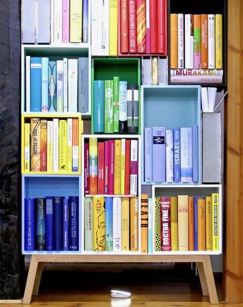 Une bibliothèque avec les livres organisés par couleurs.