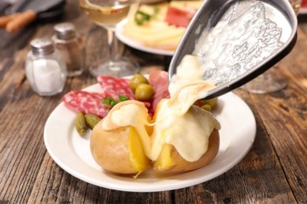 Une raclette fondue sur des pommes de terre avec de la charcuterie