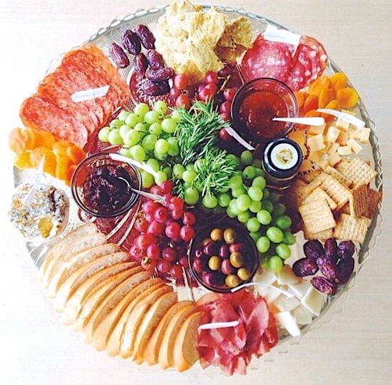 un plateau mixte complet avec de la charcuterie, du fromage et des fruits