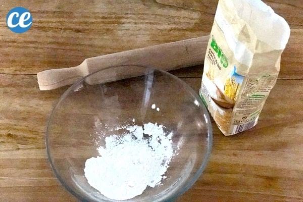 de la farine dans un saladier à côté d'un paquet de farine et un rouleau à pâtisserie