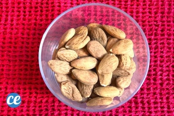 des amandes dans un bol transparents sur un fond rouge