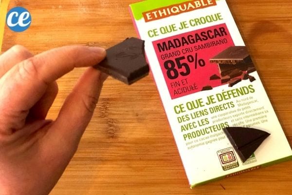 une tablette de chocolat noir à 85% et un carré tenu dans une main