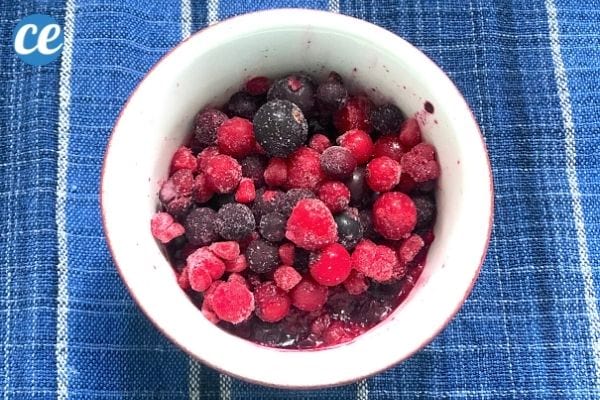 un petit bol de fruits rouges congelés sur une serviette bleue