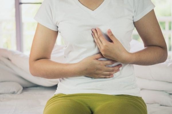 une femme se tient le ventre à cause les reflux gastriques acides