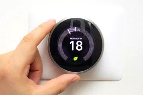 Une main qui change la température du thermostat à 18°C