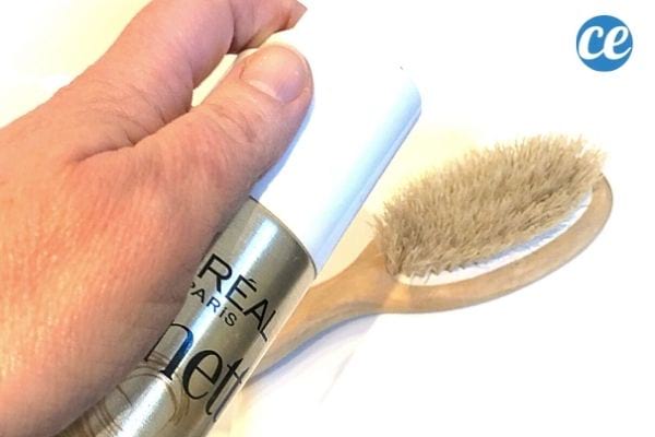 une personne met un peu de laque sur une brosse