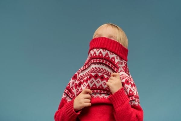 une petite fille blonde met un pull rouge