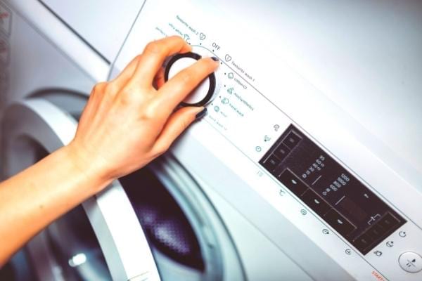 Une femme qui programme sa machine à laver à faible température pour faire des économies
