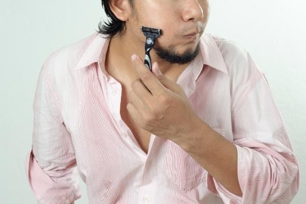 Un homme qui se rase en utilisant de l'huile d'olive comme mousse à raser