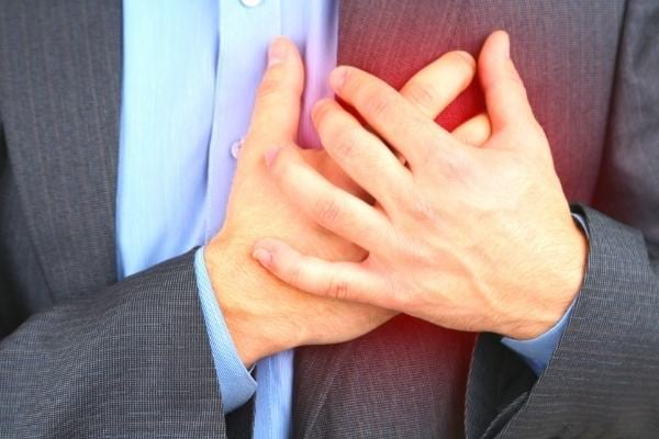 Deux mains appuyées sur un coeur en palpitation à cause d'un manque de fer