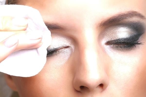 Une femme tenant un coton imbibé d'huile d'olive qui se démaquille