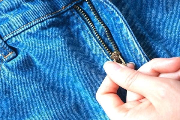 Une femme essayant de fermer une fermeture éclair cassée qui se répare avec de l'huile d'olive