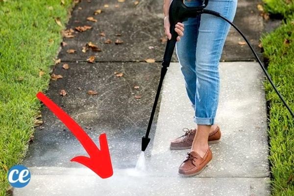 Une femme qui nettoie son allée avec un Karcher avec lance telescopique.
