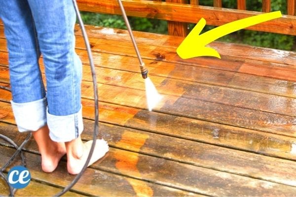 Une femme qui nettoie une terrasse en bois au Karcher.