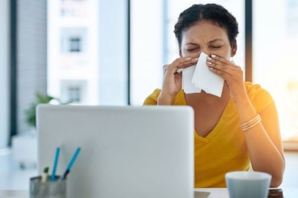 une femme se mouche devant son ordinateur