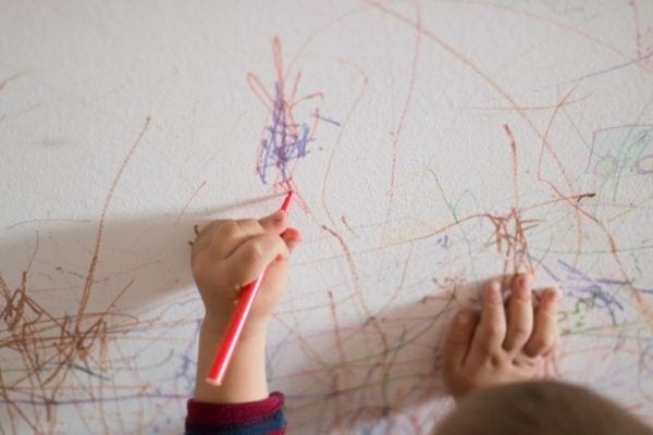a child draws on the walls with a marker