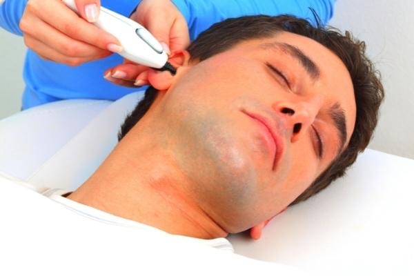 A man having his ear hair removed with an electric device