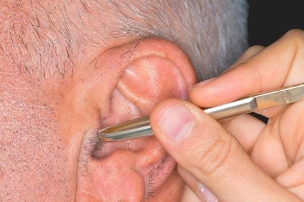 Un homme qui se fait enlever les poils d'oreille avec une pince à épiler