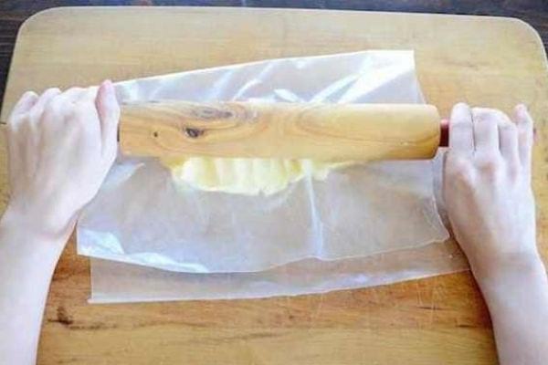 Ramoliir du beurre avec un rouleau à pâtisserie et du papier sulfurisé