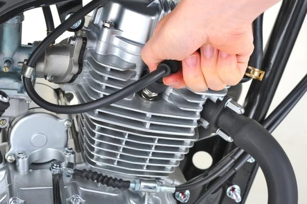 Un homme vérifiant le carburateur et les bougies pour moins consommer d'essence