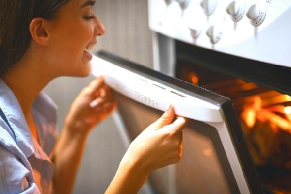 Une femme qui ouvre la porte du four sans arrêt ce qui consomme beaucoup d'électricité