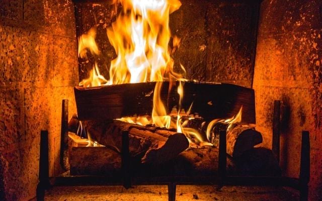 Des bûches de bois bien disposées dans une cheminée pour consommer moins de bois