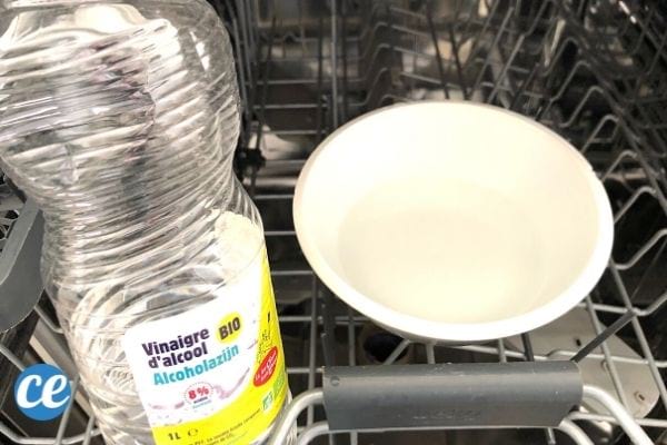 Un bol rempli de vinaigre blanc pour nettoyer un lave-vaisselle avec une bouteille de vinaigre. blanc