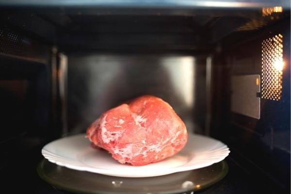 Un morceau de viande en train de décongeler dans un four qui consomme beaucoup d'électricité