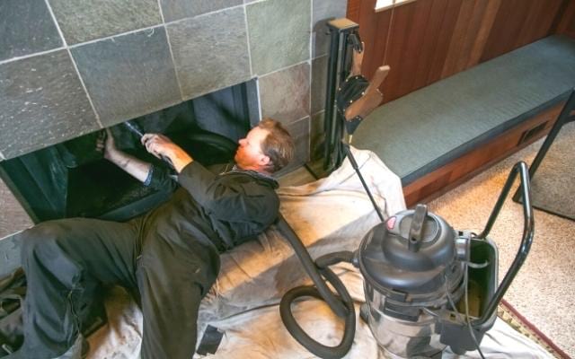 Un homme qui ramone une cheminée pour consommer moins de bois