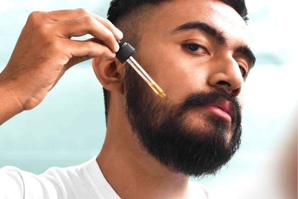 Un homme qui met de l'huile de ricin sur sa barbe