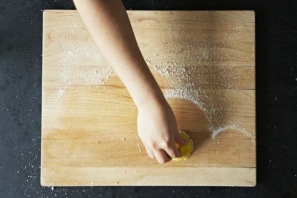 Nettoyage d'une planche à découper en bois avec du gros sel et un demi-citron 