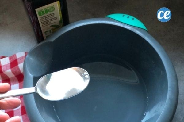 Une cuillère de bicarbonate au-dessus d'une bassine d'eau pour nettoyer les taches de gras