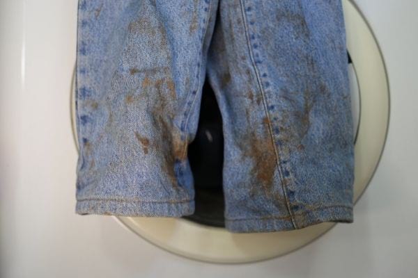 Un jean très sale devant une machine à laver